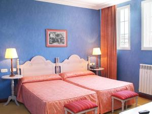 a bedroom with two beds and blue walls at Hotel San Camilo in Navarrete