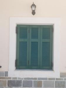 una finestra con persiane verdi su una parete bianca di Mesa Vrisi a Karpathos