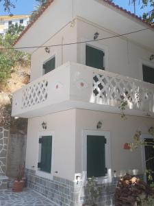 a white house with a balcony with green doors at Mesa Vrisi in Karpathos Town