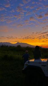 Un paio di persone in piedi accanto a un camion che osservano il tramonto di Raturinjani homestay a Selong