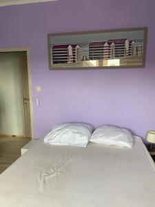 1 dormitorio con 1 cama blanca grande con una foto en la pared en Soucis au vent 2, en De Panne