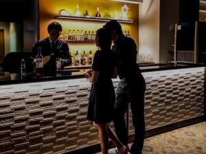 una coppia in piedi di fronte a un bar di Hotel Associa Takayama Resort a Takayama