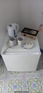 biała półka z dwoma kubkami i dzbankiem do herbaty w obiekcie The lighthouse room w mieście Stromboli