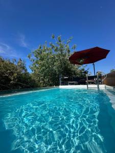 a swimming pool with an umbrella and a table and chair at SolMar Aegina with private pool - jacuzzi in Khlóï