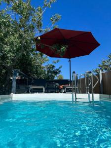 a swimming pool with a red umbrella and a swimming pool at SolMar Aegina with private pool - jacuzzi in Khlóï