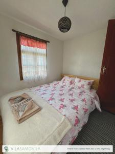 a bedroom with a bed with a floral bedspread at Traditional Cottage - Vila Samovila in Delčevo