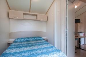 a small bedroom with a bed with a blue comforter at EurCamping Roseto Concept Glamping in Roseto degli Abruzzi