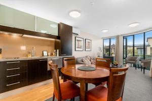 eine Küche und ein Wohnzimmer mit einem Holztisch und Stühlen in der Unterkunft The Beacon - 2 Bedroom Town Center Apartment in Queenstown