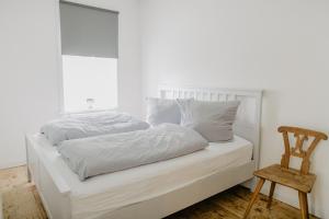 a white bed with white sheets and a wooden chair at NordseeEstate - Loft unter Reet mit Sauna in Tetenbüll