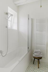 a white bathroom with a shower and a stool at NordseeEstate - Loft unter Reet mit Sauna in Tetenbüll