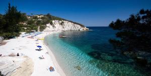 a beach with people laying on the sand and the water at Residence Capobianco in Portoferraio