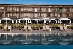 比比翁的住宿－Lino delle Fate Eco Resort，一组椅子和遮阳伞,位于游泳池旁
