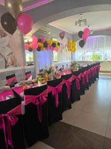 een rij tafels met roze en paarse bogen en ballonnen bij Motel Orion in Piła