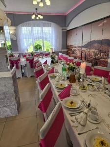 a dining room with white tables and red chairs at Motel Orion in Piła