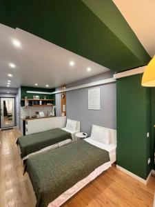 Habitación con 3 camas y pared verde. en Evergreen Apart, en Almaty