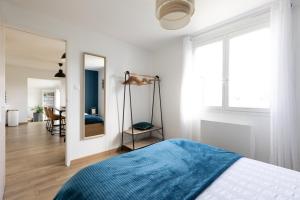 a white bedroom with a bed and a mirror at Maison Carn Portsall in Ploudalmézeau