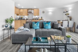 ein Wohnzimmer mit einer grauen Couch mit blauen Kissen in der Unterkunft Pluxa Globe - Spacious Apartment in JQ with parking in Birmingham
