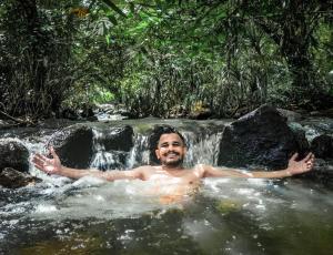 a man in a bath tub in a waterfall at Niwana Resorts kiriella in Kiriella