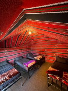 um quarto com duas camas e uma parede vermelha em Desert Bird Camp em Wadi Rum