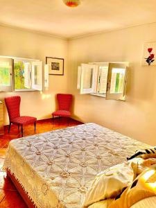 a bedroom with a bed and two chairs and windows at Linden House Etna in Aci SantʼAntonio