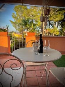 a white table with two glasses and a bottle of wine at Linden House Etna in Aci SantʼAntonio