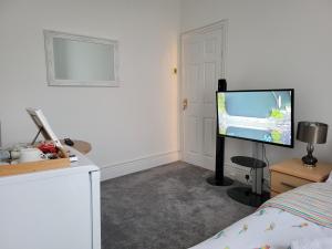 um quarto com uma cama e uma televisão de ecrã plano em A Quiet & Comfortable 4 Bedroom house em Manchester