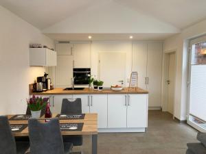 a kitchen with white cabinets and a table and chairs at Elseblick in Schüttorf
