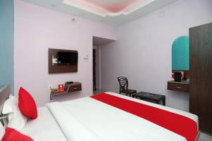 sypialnia z czerwono-białym łóżkiem i telewizorem w obiekcie Goroomgo Savashi Puri w mieście Puri