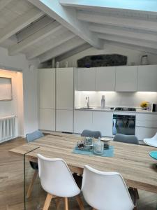 a kitchen with a wooden table and white chairs at Casa Amelia in Nesso