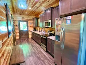 eine Küche mit Holzschränken und einem Kühlschrank aus Edelstahl in der Unterkunft South Side Serenity Cabin in Sevierville