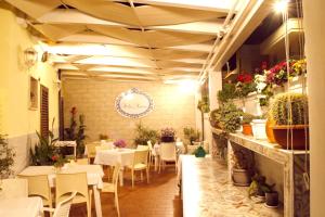 restauracja z białymi stołami, krzesłami i roślinami w obiekcie Stella Marina w mieście Porto Cesareo
