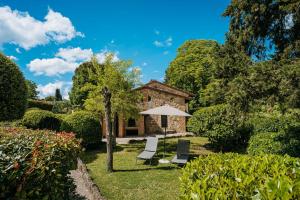 uma casa com duas cadeiras e um guarda-sol em Borgo Il Poggiaccio Residenza d'Epoca em Sovicille