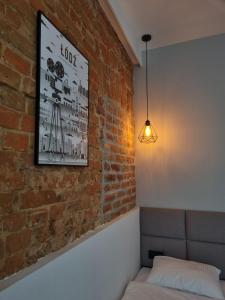 Kamienica Łódzka في لودز: غرفة بجدار من الطوب مع سرير وضوء