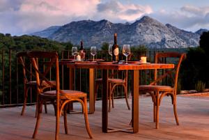 una mesa de madera y sillas con botellas de vino y copas en Tambor Del Llano, en Grazalema