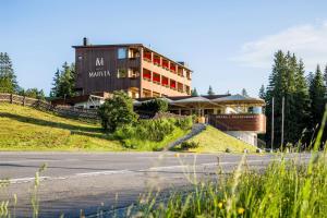 a building on a hill next to a road at Hotel Marvia in Schwarzenberg im Bregenzerwald
