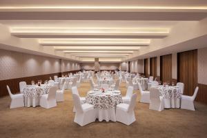 a banquet hall with white tables and white chairs at V Sarovar Portico MI Road Jaipur in Jaipur