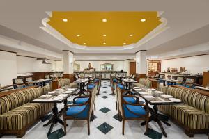 a restaurant with tables and chairs and a yellow ceiling at V Sarovar Portico MI Road Jaipur in Jaipur