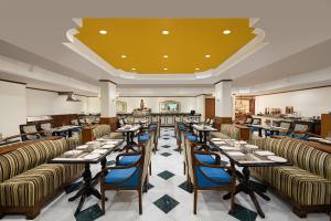 ein Restaurant mit Tischen und Stühlen und einer gelben Decke in der Unterkunft V Sarovar Portico MI Road Jaipur in Jaipur