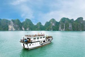 un barco en el agua con montañas en el fondo en Bhaya Halong Cruises, en Ha Long