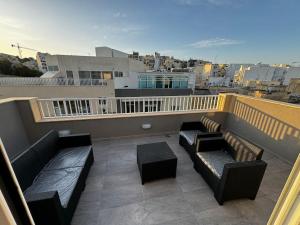 a balcony with couches and tables on a building at Moonlight Penthouse in Gzira in Il-Gżira