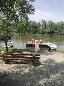 a dock with a boat on a river with a bench at Vikendica DUNAV in Novi Sad
