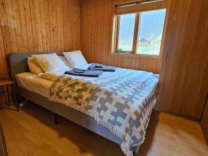 a bedroom with a bed with a blanket and a window at Cozy Cabin near Golden Circle - Private Hot Tub in Kotströnd +18 photos