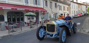 Une vieille voiture bleue qui descend dans une rue dans l'établissement Hotel Du Champ De Foire, à Saint-Aulaye