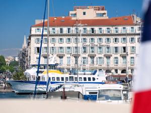 ein Boot vor einem Gebäude angedockt ist in der Unterkunft Grand Hotel Beauvau Marseille Vieux Port - MGallery in Marseille