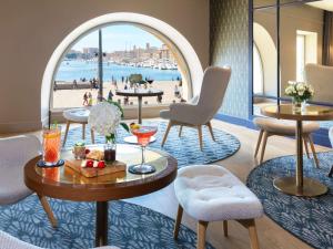 Zimmer mit Tischen und Stühlen und Blick auf den Strand in der Unterkunft Grand Hotel Beauvau Marseille Vieux Port - MGallery in Marseille