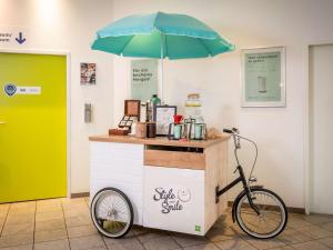 a bike parked next to a sales counter with an umbrella at ibis Styles Hamburg Alster City in Hamburg