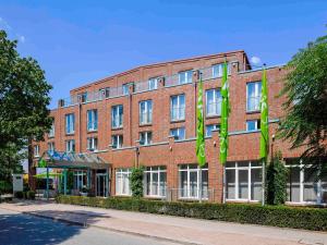 a red brick building with green flags in front of it at ibis Styles Hamburg Alster City in Hamburg