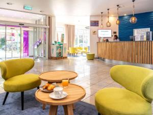 a lobby with two tables and yellow chairs at ibis Styles Hamburg Alster City in Hamburg