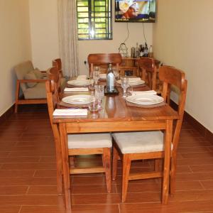 uma mesa de jantar em madeira com cadeiras e pratos em The Little Home em Arusha