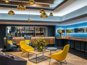 a lobby of a hotel with yellow chairs and a bar at Novotel Edinburgh Park in Edinburgh